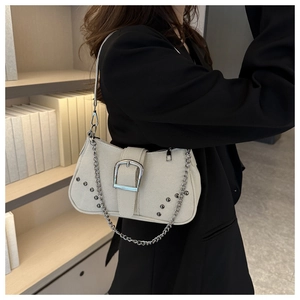 Detail of oat-colored suede shoulder bag with large silver buckle and chain accents