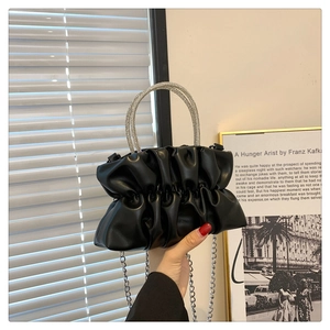 Close-up of pleated black handbag featuring rhinestone encrusted circular top handles