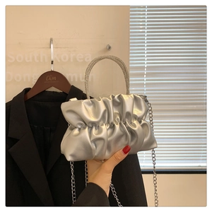 Detail of silver pleated cloud bag featuring a sparkling rhinestone handle and chain strap