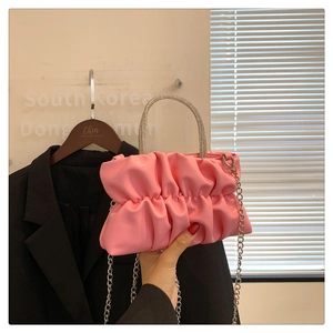 Detail of pink ruched crossbody bag with sparkling rhinestone handle and silver chain