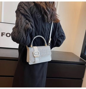 Detail of silver sequin handbag worn over the shoulder with a dark knit sweater