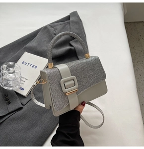 Detail view of silver grey crossbody bag with glitter flap on grey suit background