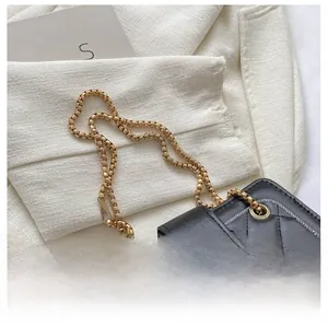 Close-up of quilted black leather bag with gold chain strap and elegant satin bow detail