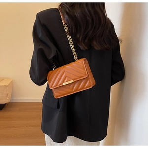 Detail of vintage brown chain bag with V-shaped quilting and gold metal hardware