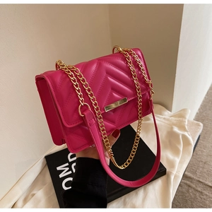 Detail of hot pink quilted shoulder bag with golden chain strap and rectangular metal clasp