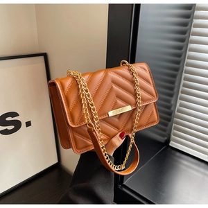 Detail of caramel chevron quilted crossbody bag with gold chain strap and metal clasp