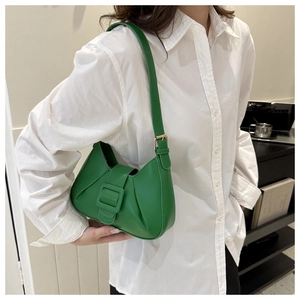 Close-up of green leather saddle bag with matte finish and square buckle detail