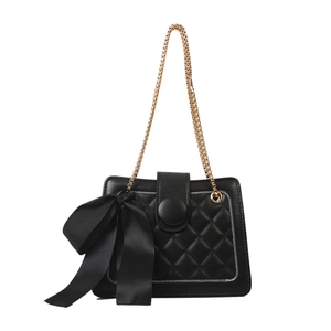Classic black quilted crossbody bag with large satin bow and gold chain strap