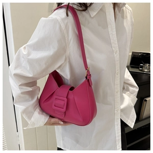 Hot pink pleated shoulder bag with oversized buckle worn by model in white shirt