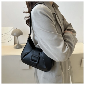 Detail view of a black minimalist underarm bag featuring a square buckle and side pleats