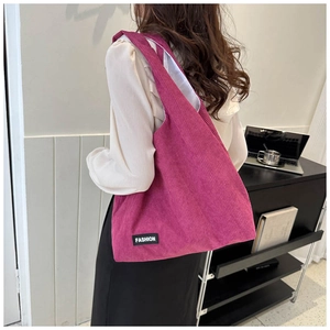 Détail du cabas en velours côtelé magenta avec texture rayée et étiquette logo mode