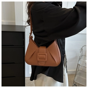 Detail showing caramel brown pleated underarm bag with a decorative square buckle