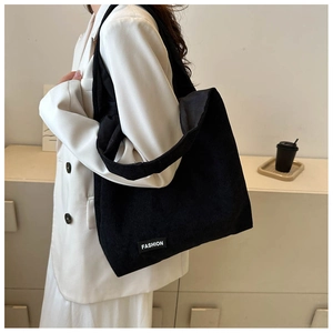 Détail d'un sac cabas en velours côtelé noir avec étiquette FASHION sur mannequin