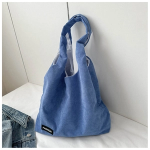 Détail du sac cabas en velours côtelé bleu avec texture rayée et étiquette mode