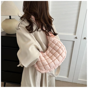 Detail of light pink quilted crescent shoulder bag showing textured nylon fabric and strap