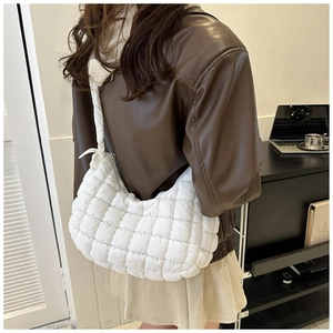 Close-up of white quilted puffer shoulder bag with soft pleated texture and wide strap