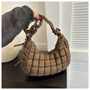 Detail of dark brown quilted puffer bag with ruffled strap and decorative bow detail