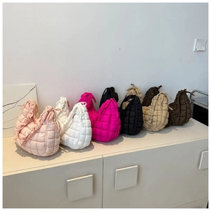 Multiple colors of quilted puffy shoulder bags with ruffle trim on a white cabinet