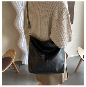 Detail of black leather hobo bag featuring a wide vintage jacquard woven shoulder strap