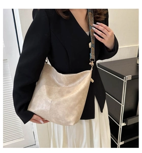 Detail of soft beige PU leather bucket bag with retro patterned wide fabric strap