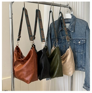 Detail of four colorful hobo bags with wide bohemian embroidered straps on a rack