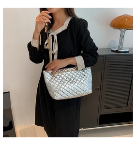 Détail du sac cabas argenté matelassé avec chaîne dorée dans un décor intérieur chic