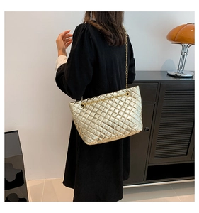 Sac fourre-tout matelassé doré avec bandoulière chaîne porté par un mannequin