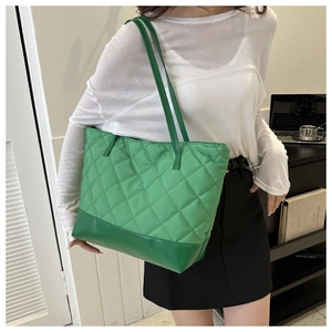 Close-up of green quilted tote bag featuring a stitched diamond pattern and leather base