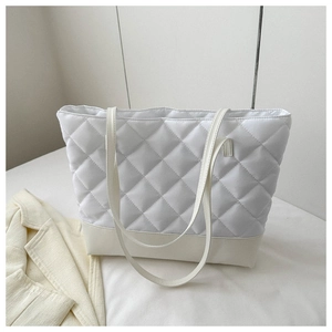 Detail of the white quilted tote bag featuring diamond patterns and a faux leather base