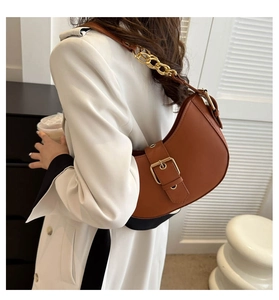 Brown leather hobo bag with gold buckle and chain strap shown on model in coat