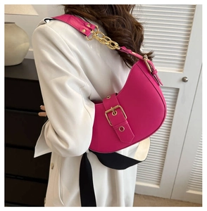Magenta crescent shoulder bag with gold hardware worn on a white blazer coat
