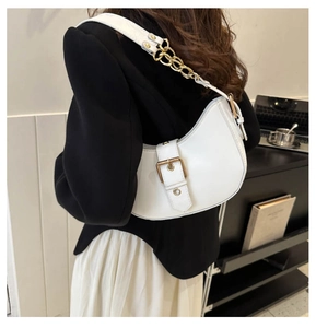 Detailed view of a white crescent shoulder bag with gold buckle and chain strap on model