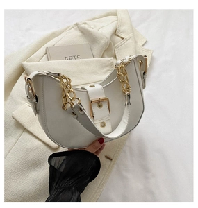 Detail view of white leather crescent bag with gold chain strap and metal clasp detail