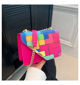 Detail of colorful geometric pattern and gold chain strap on magenta square bag