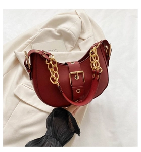 Close-up of vintage dark red leather crescent bag with bold gold chain and buckle detail