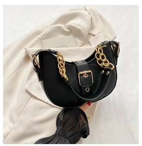 Detail of black leather half-moon hobo bag with a thick gold chain strap and buckle
