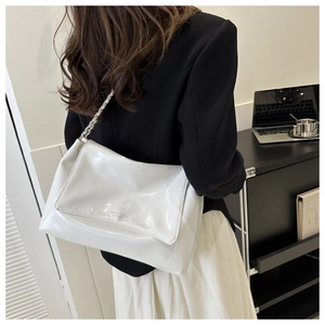 Detail view of white patent leather shoulder bag with silver chain strap and logo
