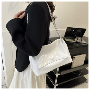 Close-up of pearl white glossy shoulder bag with silver chain strap and flap closure