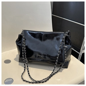 Detail of glossy black leather flap bag with silver chain strap and fashion text