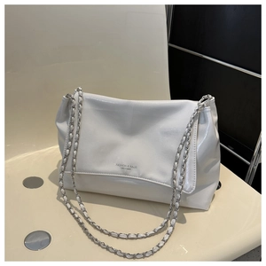 Detailed close-up of glossy white PU leather bag featuring silver chain and brand logo