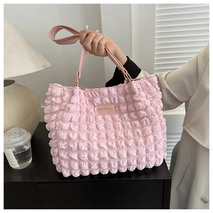 Detail shot of pink pleated texture fabric and gold fashion plaque on a stylish tote bag