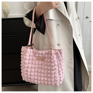 Detail of pink bubble texture shoulder bag with FASHION label on white trench coat