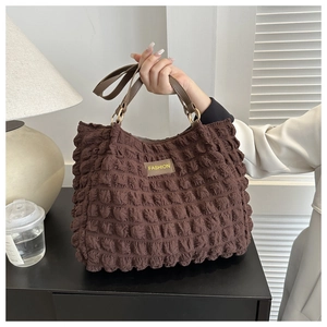 Close-up of brown bubble texture fabric and leather handle with golden metal rings