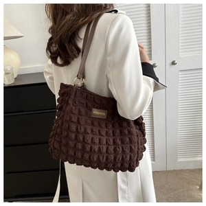 Detail of dark brown ruched popcorn texture tote bag with leather shoulder strap