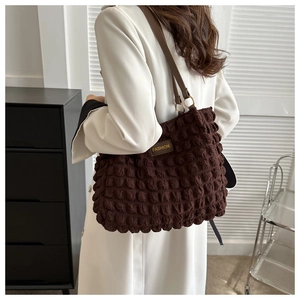 Close-up of brown bubble textured fabric tote with a fashion logo tag and leather strap