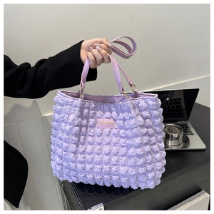 Detailed view of lavender bubble textured tote bag featuring a gold fashion logo plaque