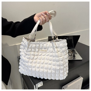 Macro shot of white quilted bubble texture and FASHION label on a chic tote bag