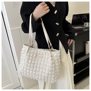 Detail of white pleated tote bag with bubble texture and golden Fashion leather label