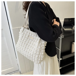 Detailed close-up of white ruched shoulder bag with Fashion label and metal ring strap