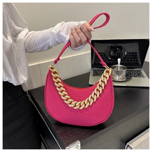 Detail of fuchsia crescent bag with croc-embossed texture and chunky gold chain handle
